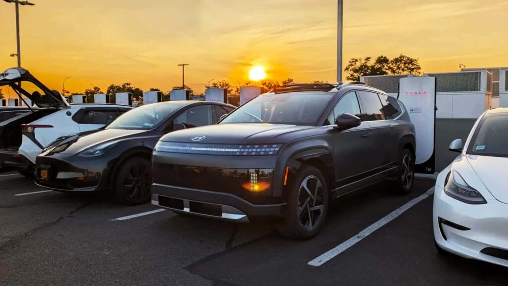 Elektriske biler parkeret ved en Tesla-ladestation i solnedgangen