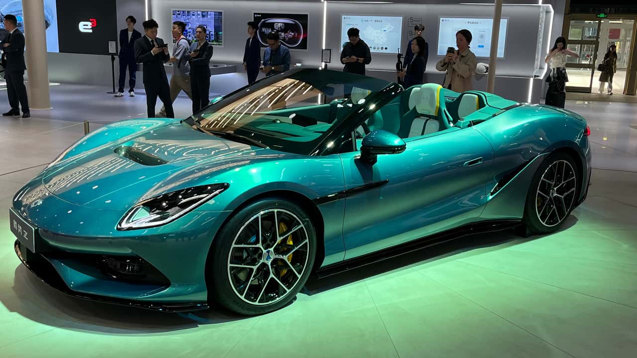 Elektrisk sportsvogn udstillet på bilmesse med mennesker i baggrunden