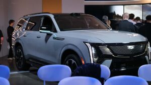 Præsentation af ny elektrisk SUV på teknologiudstilling omgivet af tilskuere