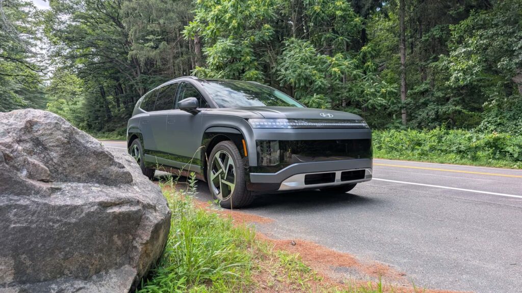 Elektrisk SUV parkeret ved landet vej omgivet af skov