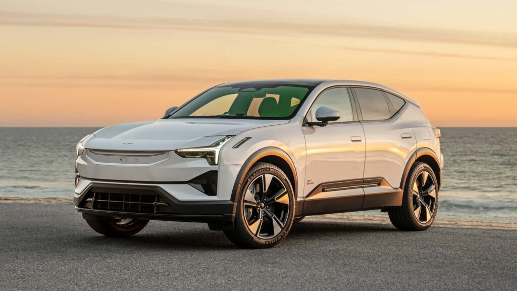 Hvid elektrisk SUV ved havet i solnedgang