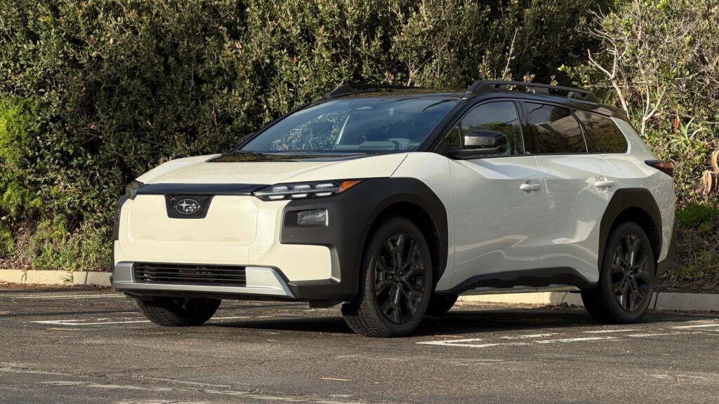 Hvid elektrisk SUV parkeret foran frodig grønt buskads