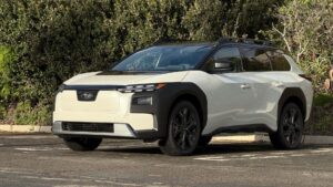 Hvid elektrisk SUV parkeret foran frodig grønt buskads