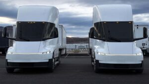 To Tesla Semi lastbiler parkeret på en åben plads foran et industriområde.