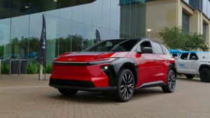 Rød elektrisk bil parkeret foran glasbygning
