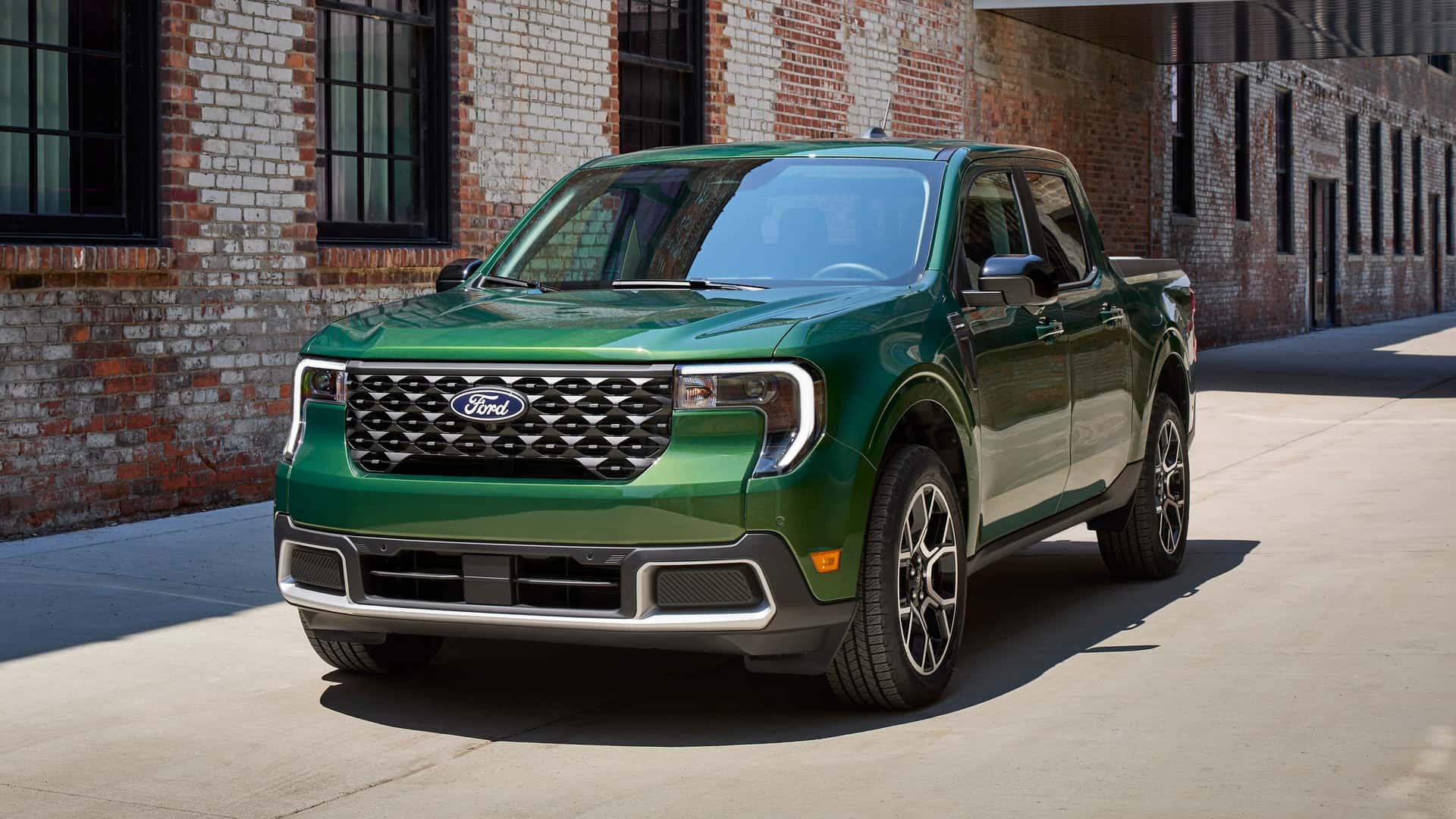 Grøn Ford pickup-truck parkeret ved en murstensbygning