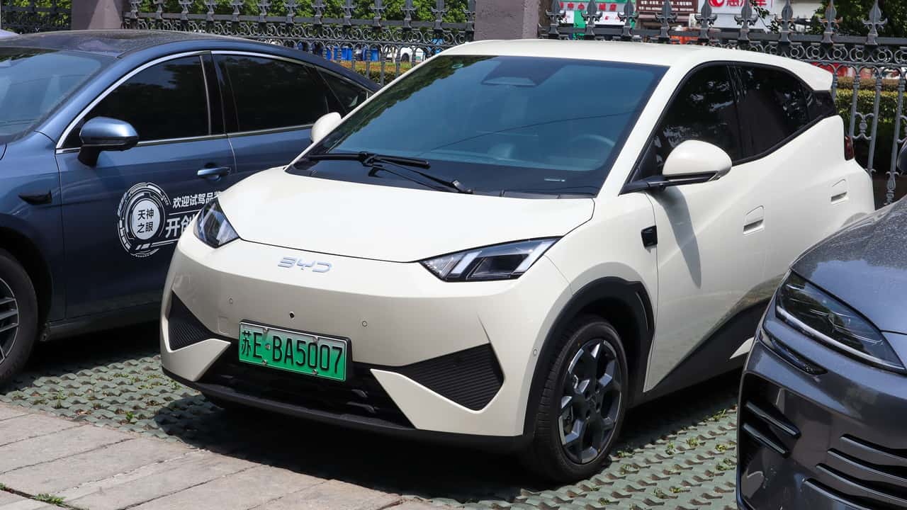 Hvid elektrisk bil parkeret mellem to andre biler