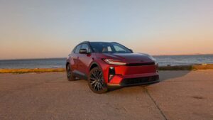 Rød elbil ved vandkanten i solnedgang