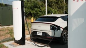 Elbil oplader ved en Tesla ladestation i grønne omgivelser