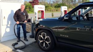 Person oplader en Rivian elbil ved en Tesla ladestation