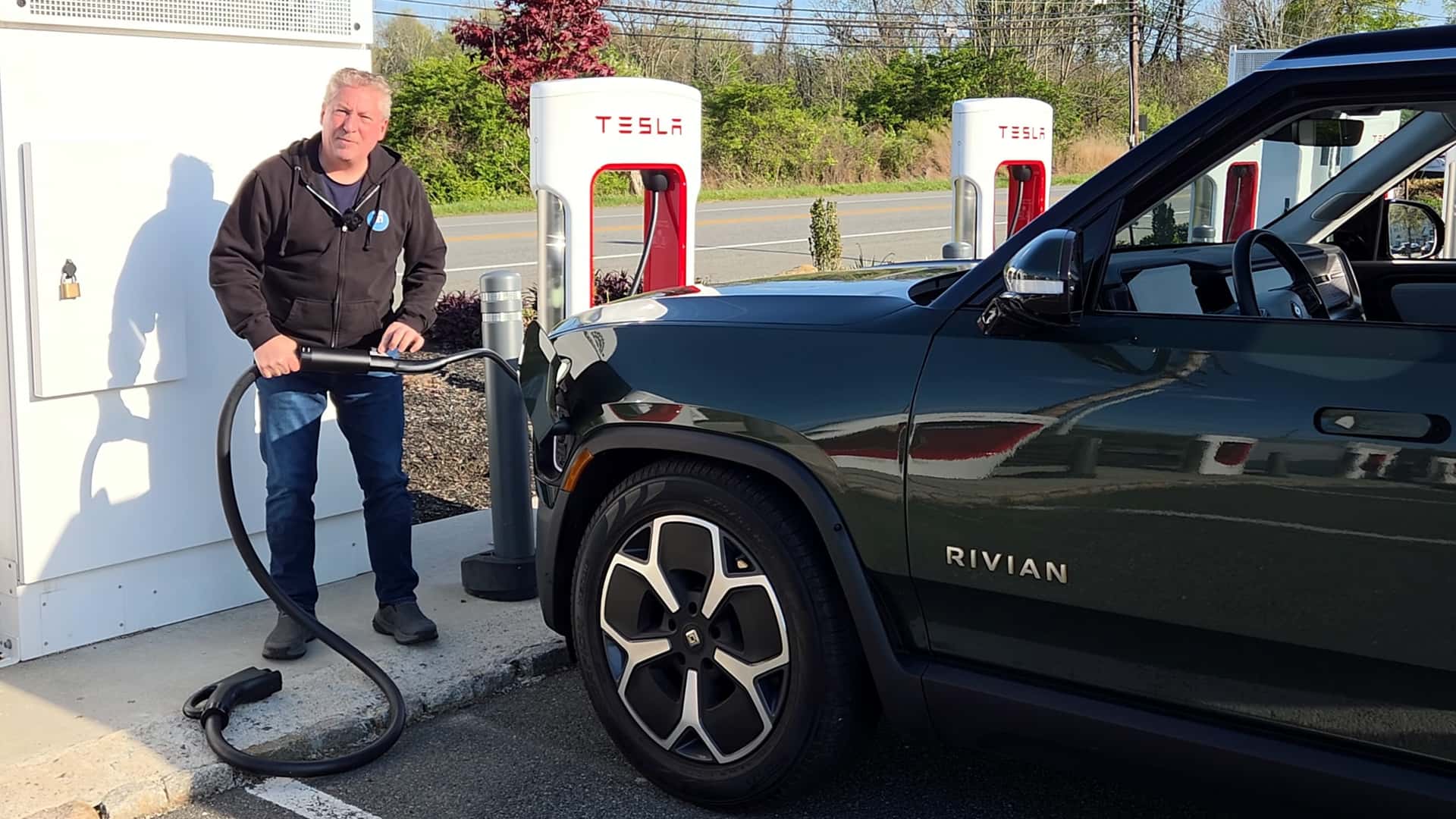 Person oplader en Rivian elbil ved en Tesla ladestation