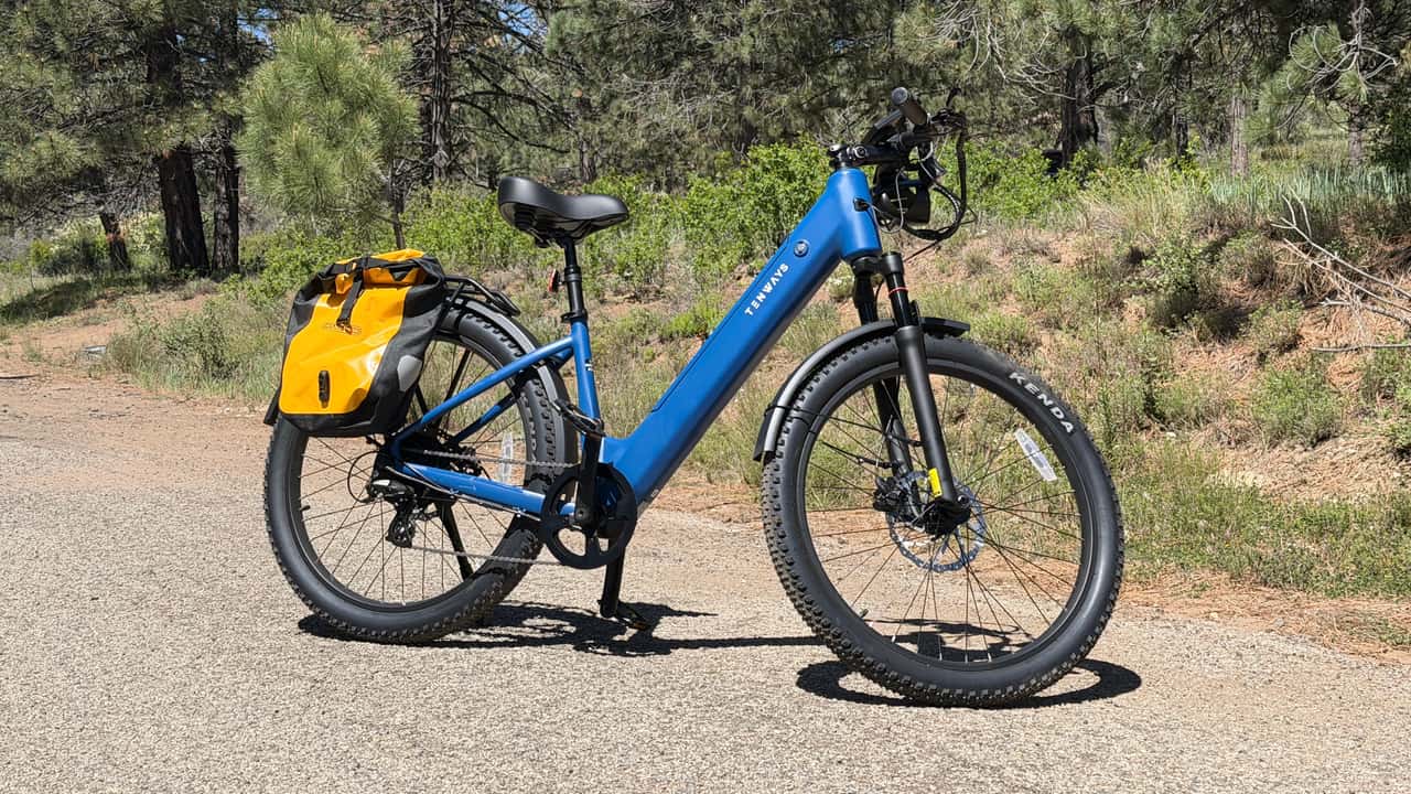 Elektrisk blå cykel med gul taske på grusvej i naturen