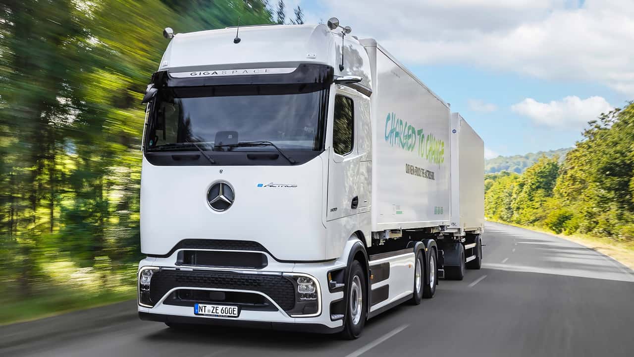 Elektrisk lastbil af mærket Mercedes på vej gennem en skov omgivet af grønne træer