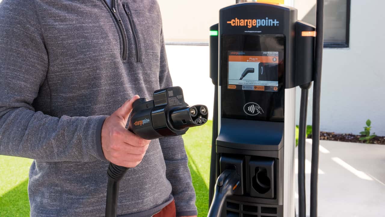 Person der holder en elektrisk biloplader ved en ChargePoint ladestation