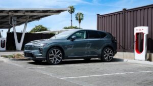Elektrisk SUV oplader ved Tesla ladestation under klar himmel
