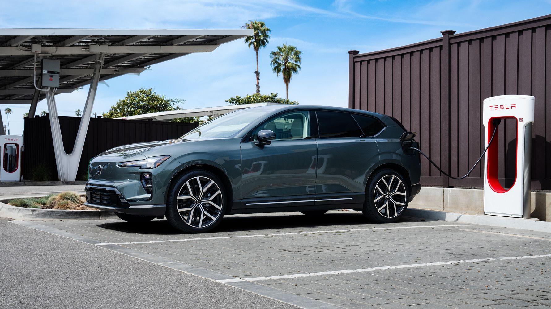 Elektrisk SUV oplader ved Tesla ladestation under klar himmel