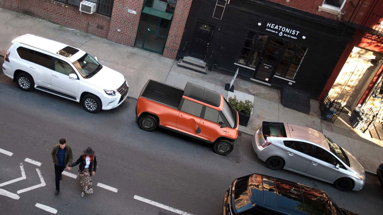 Orange elektrisk pickup parkeret mellem biler