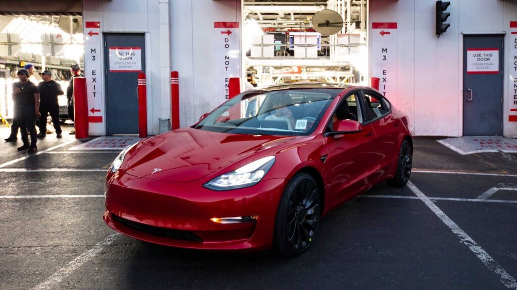 Rød Tesla Model 3 parkeret ved fabrikudgang