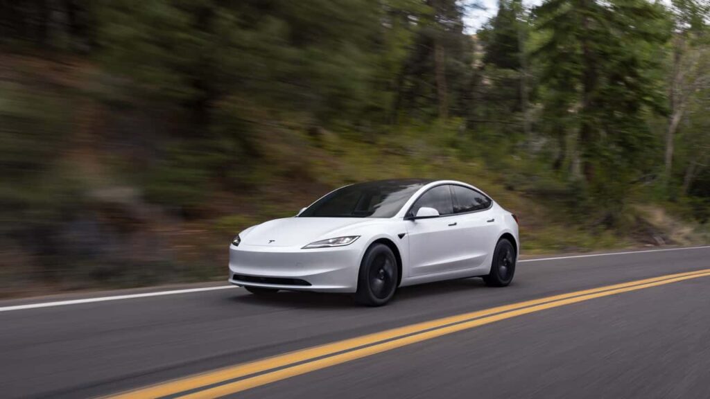Tesla sedan kører på vej i skovområde