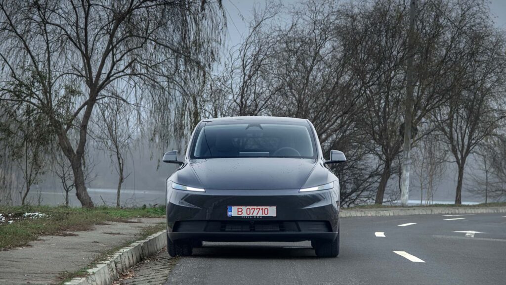 Tesla bil parkeret på en vej med træer i baggrunden