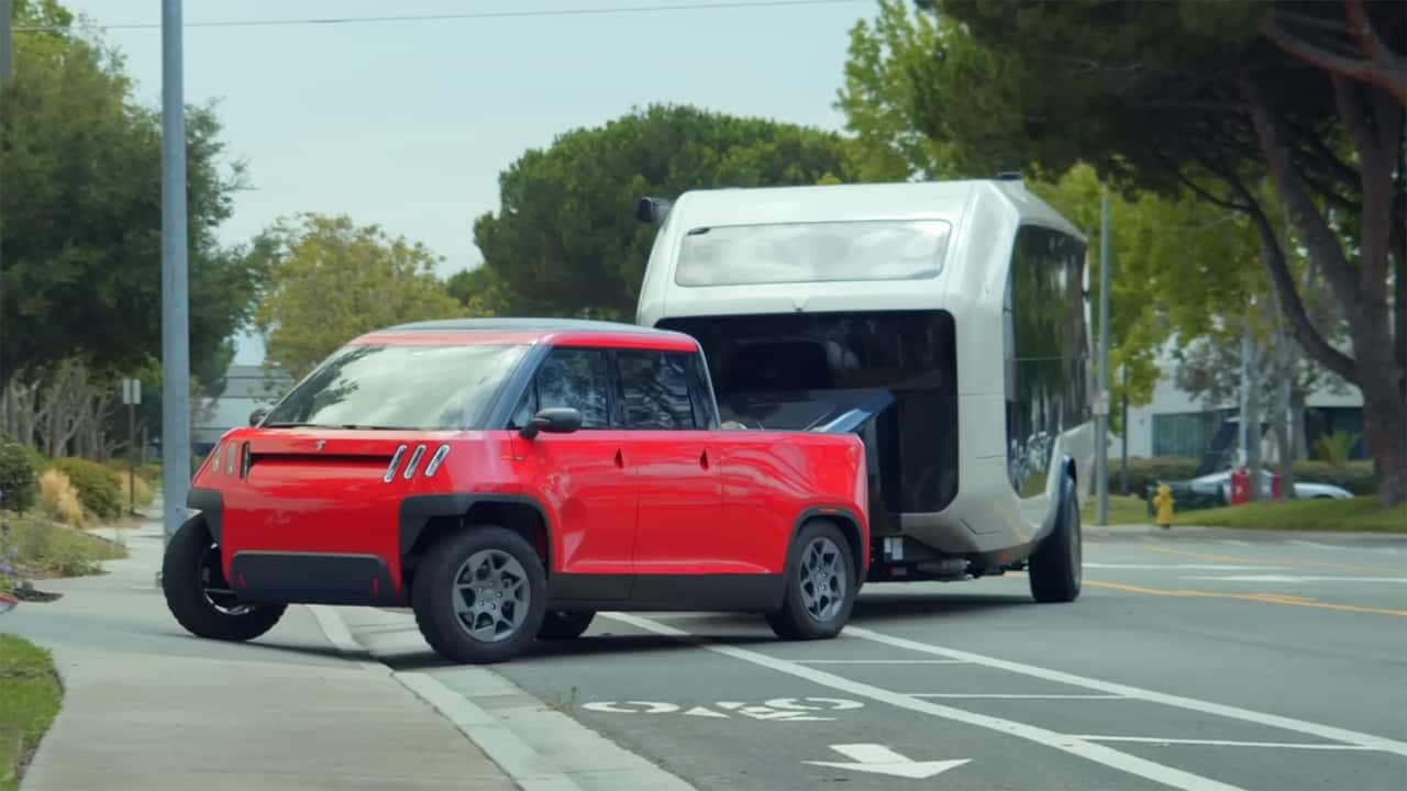 Rød kompakt elektrisk pickup med trailer på vej