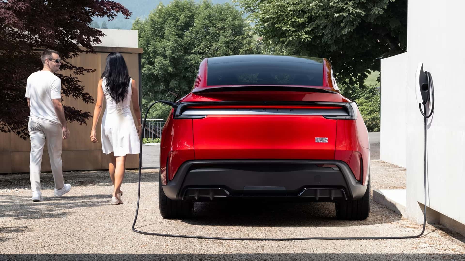 Rød Tesla bagfra under opladning ved hus