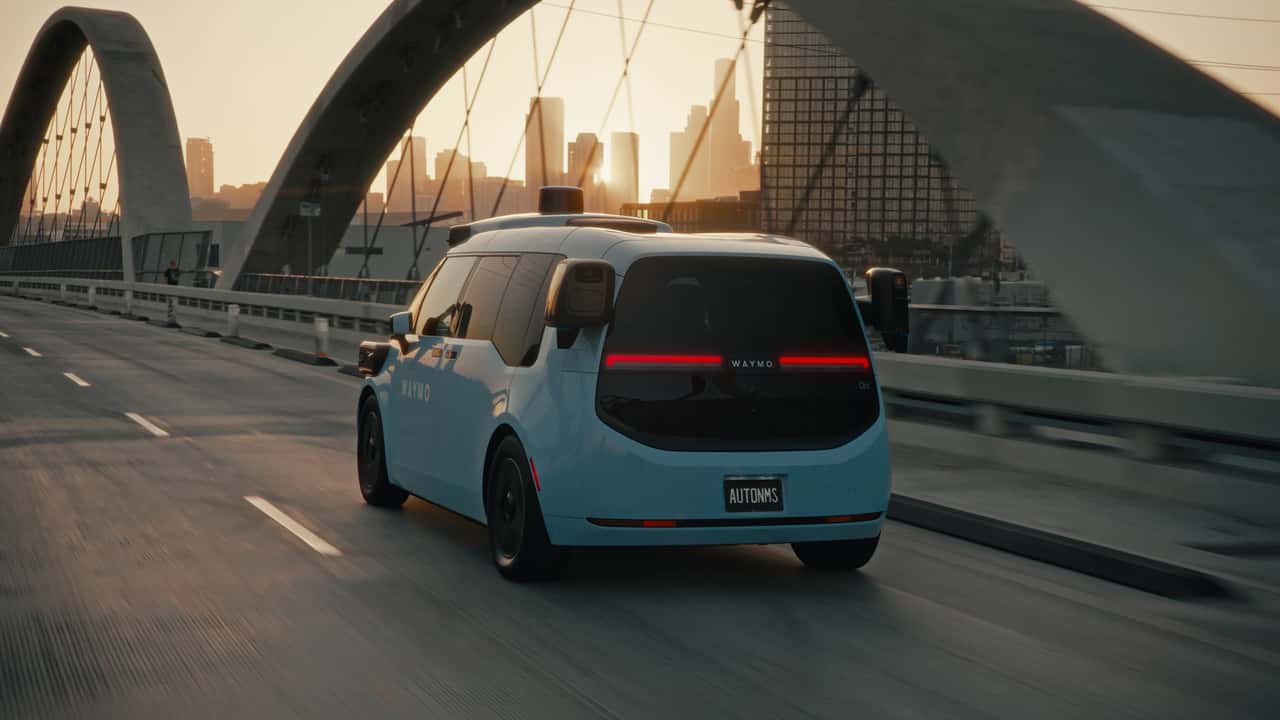Waymo selvkørende bil på bybro ved solnedgang