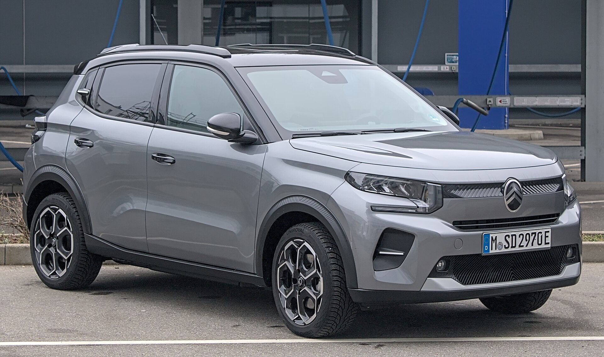 Grå Citroën ë-C3 parkeret foran en vaskehal