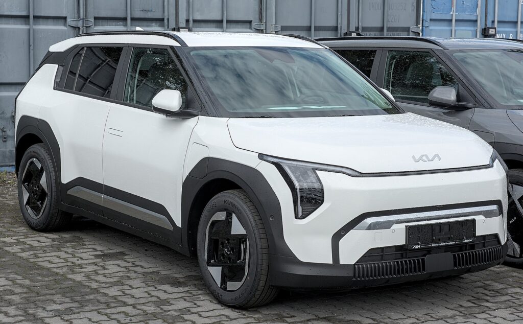 Hvid Kia EV3 parkeret på en brostensbelagt plads