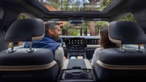 Indvendig i en elektrisk SUV, to personer kigger på dashboard