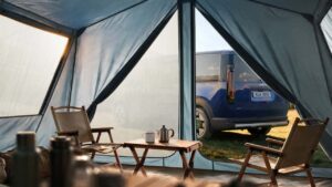 Kia EV parkeret ved campingområde set fra telt