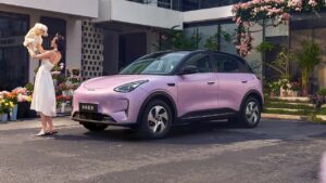 Elektrisk SUV foran hus med kvinde og hund
