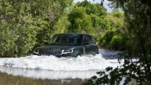 Range Rover kører gennem vand i skovområde