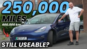 Tesla Model 3 parkeret med ejer ved siden af
