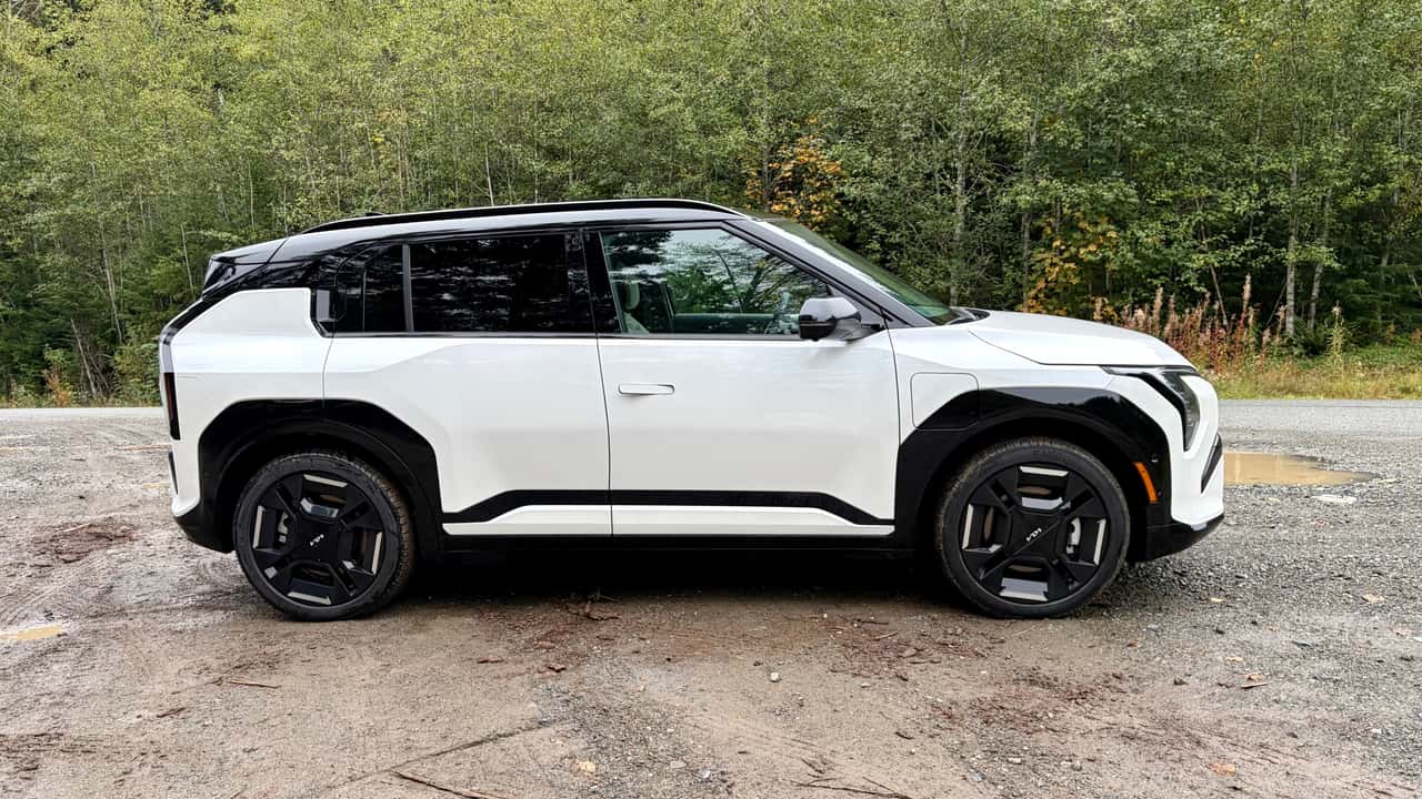 Hvid elektrisk SUV ved skovklædt vej