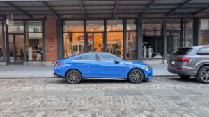 Blå Mercedes-Benz EQE parkeret foran butik