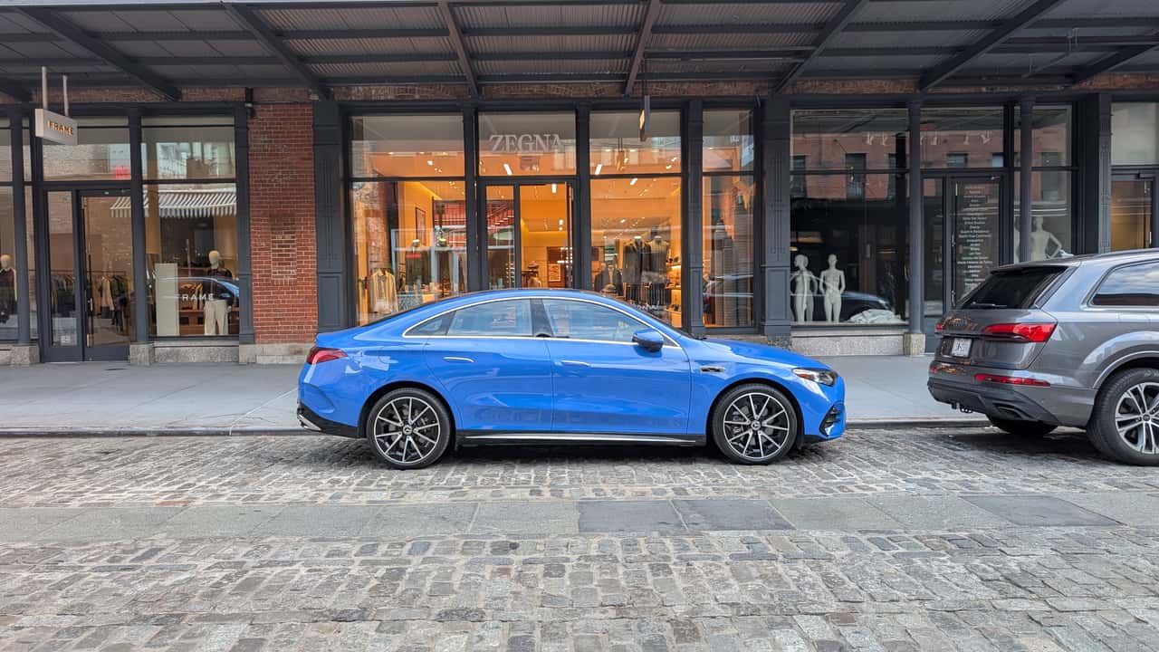 Blå Mercedes-Benz EQE parkeret foran butik